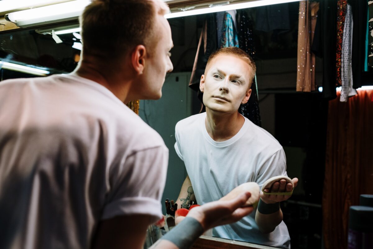 Guy looking at a mirror checking out his makeup for a blog on 5 ways to control oily skin